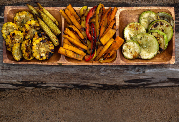 decomposed the grilled vegetables into a sectional wooden tray on old gray wood - Foto, Bild