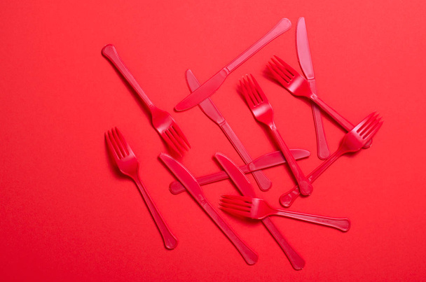 Red Forks and Knives on Bright Orange Background, Single Use Cutlery, Food Concept - Фото, изображение