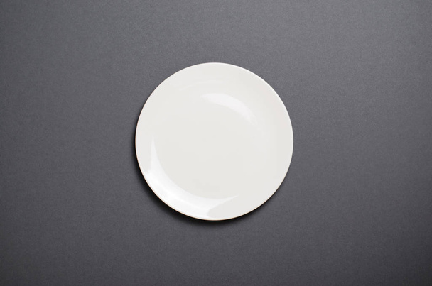 Άδειο λευκό πιάτο κάτοψη σε γκρι φόντο, άδειος χώρος, έννοια των τροφίμων - Φωτογραφία, εικόνα