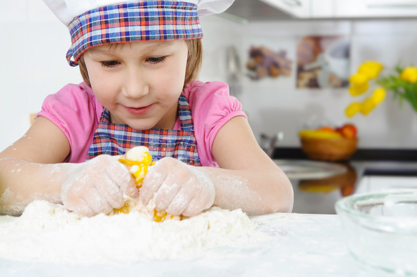 Cute little girl in apron cooking cookies - Zdjęcie, obraz