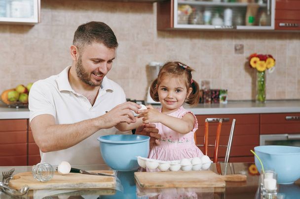 Dziecko dziewczynka pomaga człowiekowi gotować ciasteczka świąteczne imbir, przerwy jajka do miski, przy stole. Szczęśliwa rodzina tata, córka dziecko gotowanie żywności w weekend rano. Wakacyjny dzień ojca. Dzieciństwa rodzicielstwa - Zdjęcie, obraz
