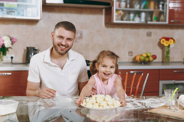 Malá holka kluk pomoci muže vařit líný knedlíky v lehké kuchyni u stolu. Šťastné rodiny táta, Dcera dítě vaření potravin v víkendové ráno doma. Den otců svátek. Koncept dětství rodičovství - Fotografie, Obrázek