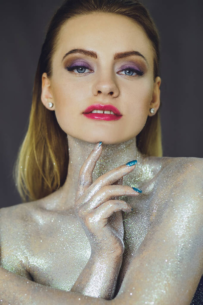 Beautiful girl with creative glitter makeup with sparkles. Beauty is an art face. Photo taken in the studio. - Valokuva, kuva