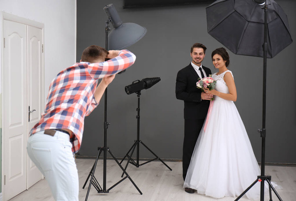 Professional photographer taking photo of wedding couple in studio - Zdjęcie, obraz