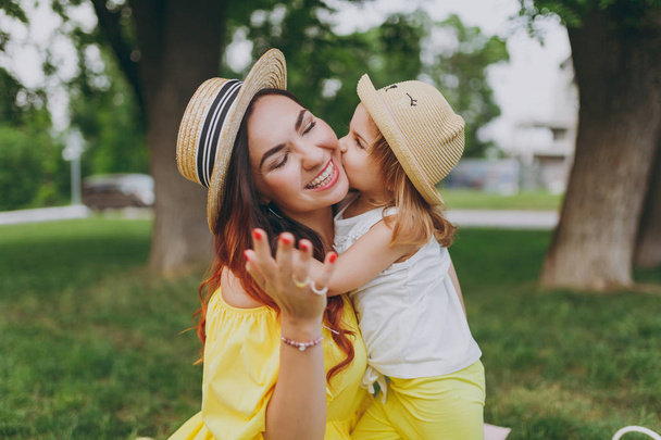 小さなかわいい子赤ちゃん女の子キス頬と抱擁、黄色い服で笑顔の女性と抱擁は、緑豊かな公園で楽しい時を過します。母親、子供の幼い娘。母の日、愛の家族、親、子供の頃 - 写真・画像