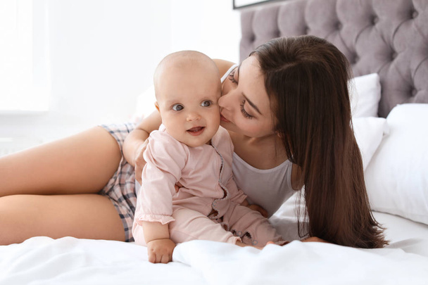 Young mother with her cute baby girl on bed at home - Φωτογραφία, εικόνα