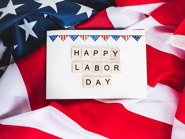 Notepad with blank page, wooden letters of the alphabet in the form of the words Labor Day on the background of the US Flag. Top view, close-up - Fotografie, Obrázek