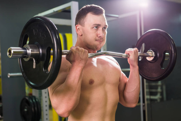 Musculoso joven levantando pesas en el gimnasio
 - Foto, Imagen