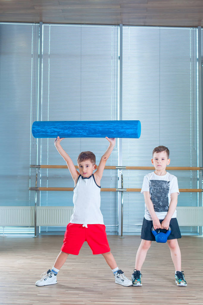 Group of children doing kids gymnastics in gym with teacher. Happy sporty children in gym. foam roller - Zdjęcie, obraz