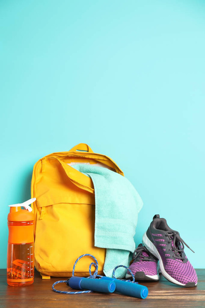 Sports bag and gym equipment on wooden floor against color background - Foto, Imagem