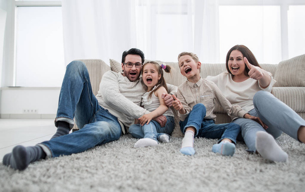 happy family sitting on the carpet in the living room - Foto, Bild
