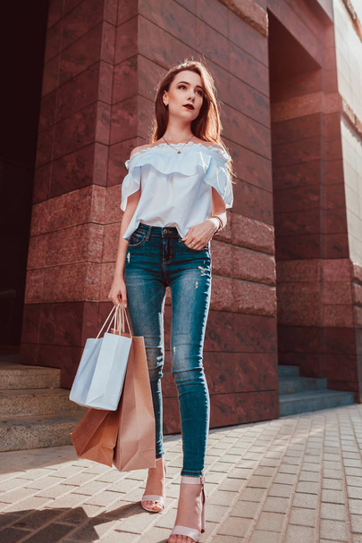 Mulher bonita e elegante com sacos de compras andando na rua da cidade no verão. Modelo magro usando fechamento e acessórios. Sexta-feira negra
 - Foto, Imagem