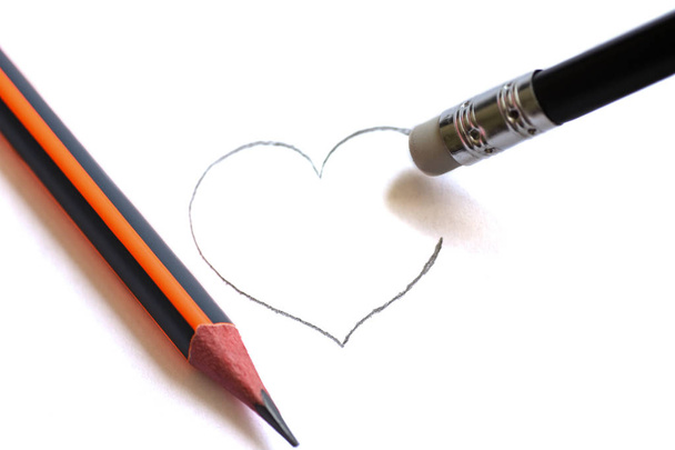Washing on a pencil erases the painted heart. Simple pencils symbolize ruined love - Photo, Image