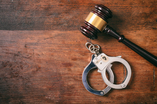 Law and order concept. Handcuffs isolated and a gavel with copy space, on a wooden background. - Foto, Imagem
