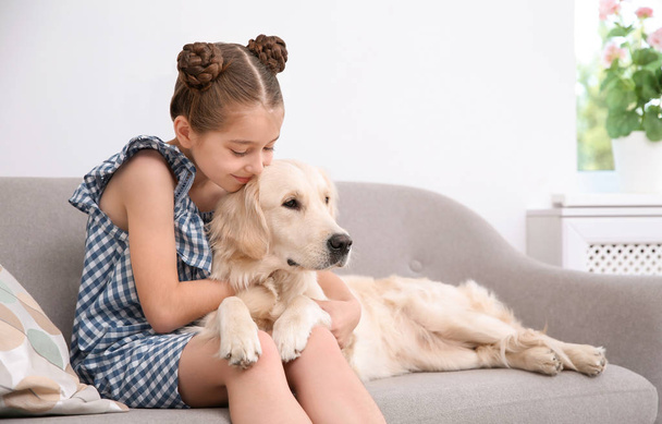 Cute little child with her pet on sofa at home - Foto, immagini