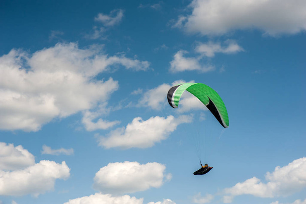 Paraglider vliegen in de blauwe lucht tegen de achtergrond van wolken. Paragliden in de hemel op een zonnige dag. - Foto, afbeelding