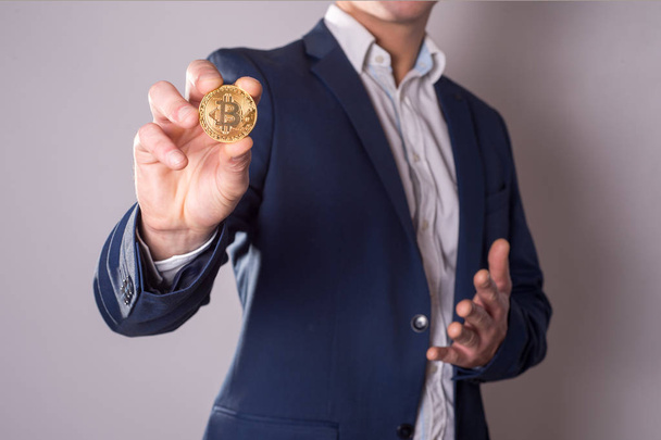 Golden Bitcoin in a man hand, Digitall symbol of a new virtual currency - Фото, изображение