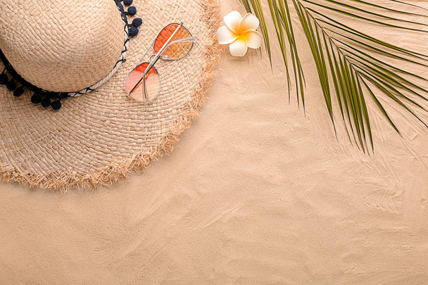 Flat lay composition with stylish hat, flower and tropical leaf on sand - Fotó, kép