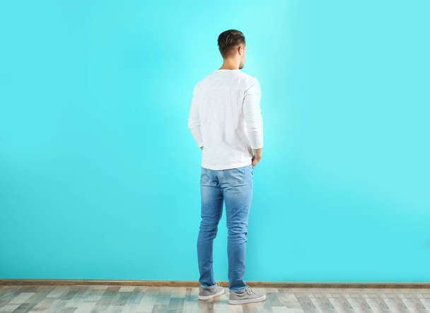 Young man in stylish jeans near color wall - Фото, зображення