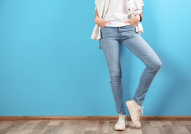 Young woman in stylish jeans near color wall - Foto, imagen