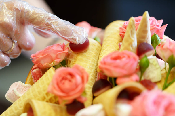 Processo de decoração de um belo buquê composto por rosas rosa e vários doces
 - Foto, Imagem