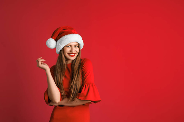 Young beautiful woman in Santa hat on color background. Christmas celebration - Foto, imagen