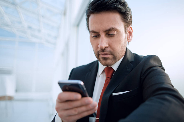close up.businessman with a smartphone looking at the camera - Foto, Imagen