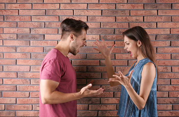Young couple having argument near brick wall. Relationship problems - Φωτογραφία, εικόνα