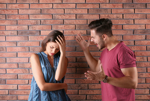 Young couple having argument near brick wall. Relationship problems - Valokuva, kuva