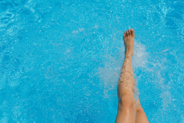 schöne weibliche Füße, Wasserspritzer und türkisfarbenes Poolwasser - Foto, Bild