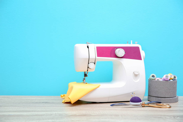 Sewing machine on table against color background - Foto, Bild