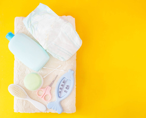 Baby bathing accessories, diaper, yellow background - Foto, afbeelding