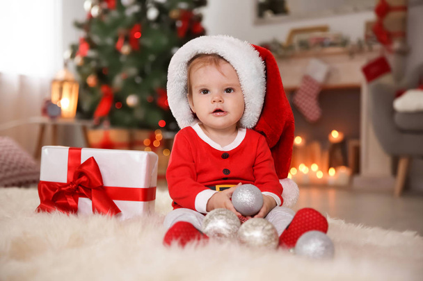 Cute little baby in Christmas costume sitting on fur rug at home - Фото, изображение