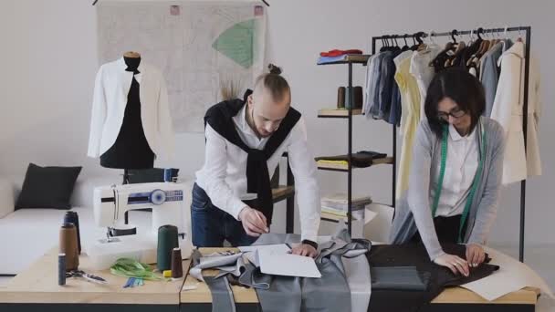 The designer of clothes and dressmaker develops a new collection of clothes at the modern small atelier. Successful completion of the working day. Fashion designers are focused on their work - Materiał filmowy, wideo