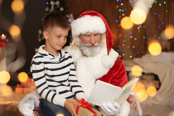 Маленький ребенок с Дедом Морозом читает Рождественскую историю дома
 - Фото, изображение