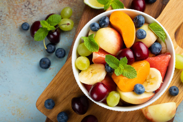 Tál egészséges friss gyümölcssaláta rozsdás kék háttérrel. Szemközti nézet - Fotó, kép