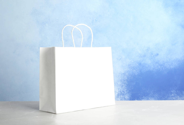 Mockup of paper shopping bag on table against color background - Foto, Imagen