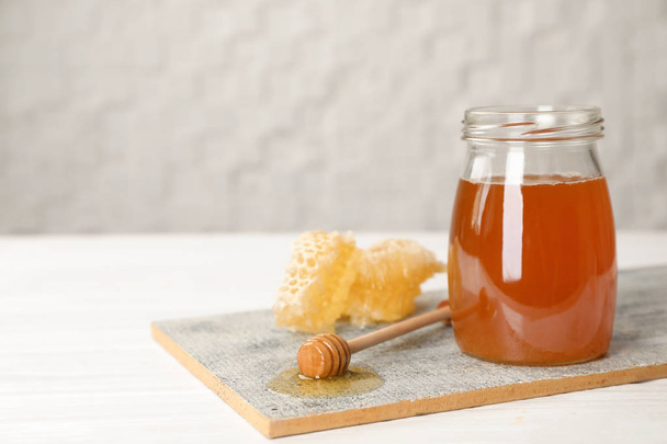 Jar of tasty fresh honey and dipper on board - Foto, Imagen