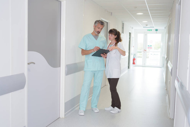 medical staff looking at clipboard in hospital corridor - Fotografie, Obrázek