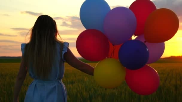boldog asszony léggömbökkel fut a búzamező naplementekor - Felvétel, videó