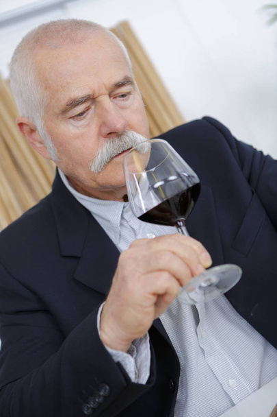 mature sommelier smell at a glass of a red wine - Photo, Image