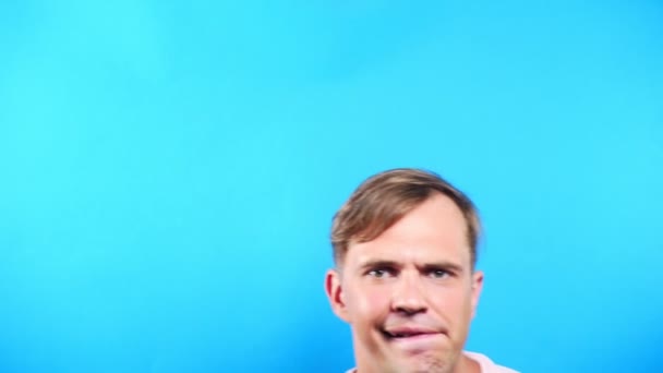 Young man on a colored blue background. portrait. emotions and gestures. 4k, close-up. Slow motion. the guy looks in the camera with interest. whats happening . - Filmmaterial, Video
