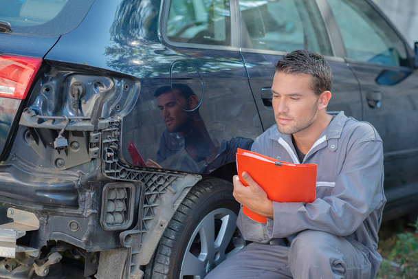 Mechanic inspecting a damaged car - Zdjęcie, obraz