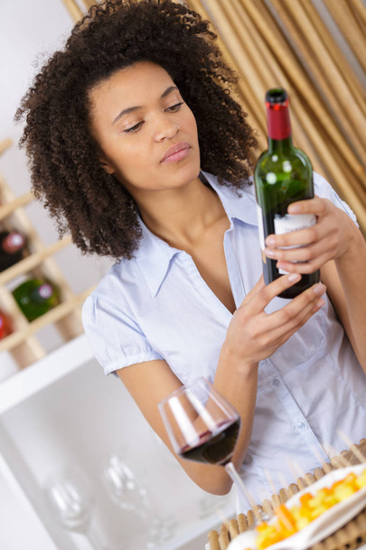 attractive young woman holding bottle of red wine - Foto, Imagen