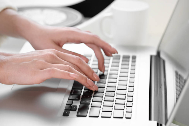 Выборочный фокус, яркое солнце. Обрезанный снимок женских рук с красными ногтями, печатающих на клавиатуре во время общения с друзьями с помощью ноутбука, сидящего у окна
. - Фото, изображение
