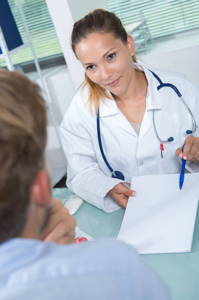 female doctor showing document to her male patient - Zdjęcie, obraz
