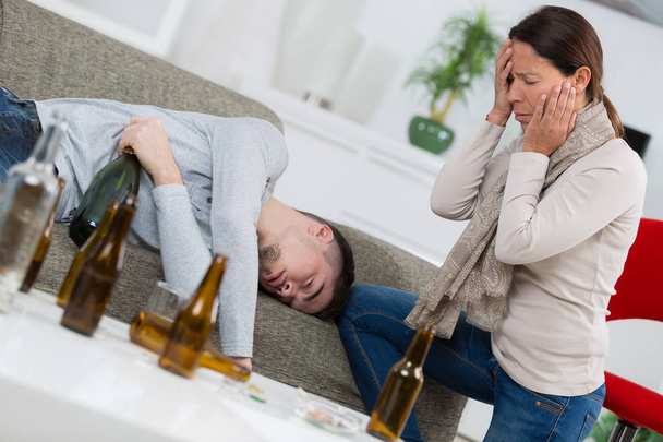 Distraught mother finding son passed out from alcohol - Фото, изображение