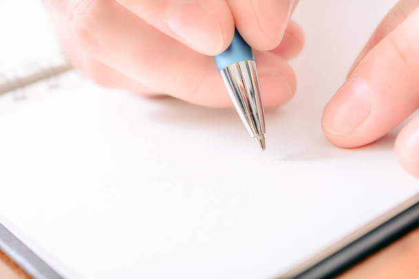 Primer plano de un hombre escribiendo a mano en un organizador en blanco con un Biro
 - Foto, Imagen