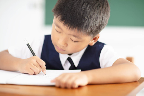  niño pequeño escribiendo tareas en el aula
 - Foto, imagen