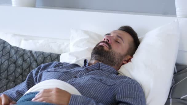 Młody broda człowiek śpi w łóżku - Materiał filmowy, wideo